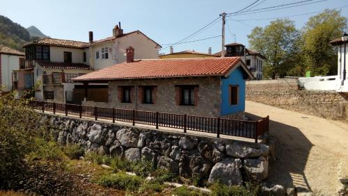una casa en una pared de piedra junto a una calle en La Fragua, en Nueva de Llanes