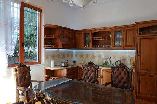 a kitchen with wooden cabinets and a glass table and chairs at RADOVICI LUX APARTMENTS in Radovići