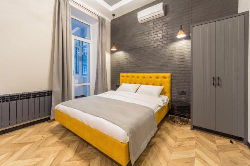 a bedroom with a yellow bed and a brick wall at Secret Apartments in Kyiv