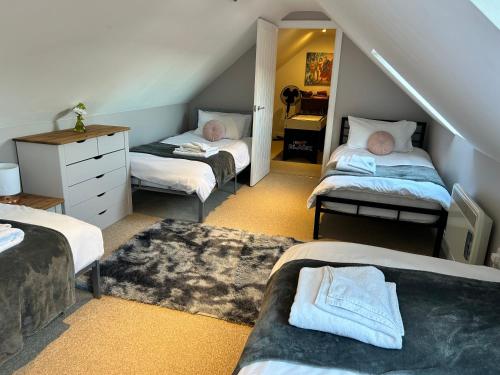 a attic room with three beds and a mirror at The Dairy, Bramble Farm Cottages in Ferndown