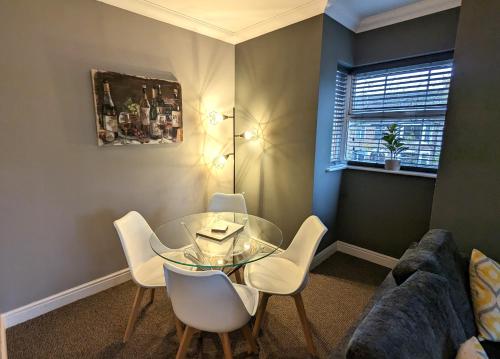 un soggiorno con tavolo in vetro e sedie bianche di Stylish Modern Apartment, FREE SECURE Parking a Allesley