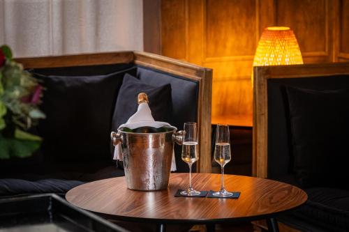 a table with two wine glasses and a bucket at Le Nouvel Hôtel in Oyonnax