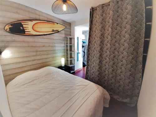 - une chambre avec un lit et une planche de surf sur le mur dans l'établissement Appartement cosy, 4 pers, proche plages et centre, BBQ, parking, Wifi inclus - FR-1-239-943, à Capbreton