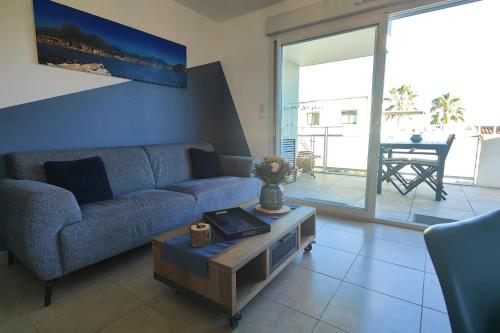 sala de estar con sofá azul y mesa en Bright apartment - sea view, en Fréjus