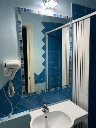 Baño de azulejos azules con lavabo y espejo en beb Rosy, en Nápoles