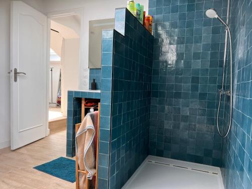La salle de bains est pourvue de murs carrelés bleus et d'une douche. dans l'établissement Maison lumineuse avec jardin - Proche plage d'Eyrac et commerces - FR-1-420-133, à Arcachon