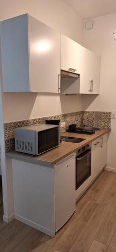eine Küche mit weißen Schränken und einer Mikrowelle in der Unterkunft Studio Winston in Dinard