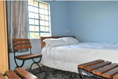 Schlafzimmer mit einem Bett, einer Bank und einem Fenster in der Unterkunft The D'Lux Home, Homa Bay in Homa Bay