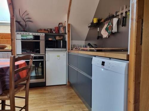 a kitchen with white appliances and a table at Chalet climatisé grande terrasse parking privé in Coublevie