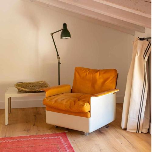 an orange chair in a living room with a lamp at La Alberca Casa con jardín y piscina in Tenzuela