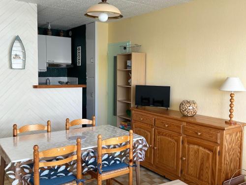 d'une salle à manger avec une table, des chaises et une télévision. dans l'établissement Appartement 1 chambre front de mer avec balcon et parking à St Hilaire de Riez - FR-1-652-38, à Saint-Hilaire-de-Riez