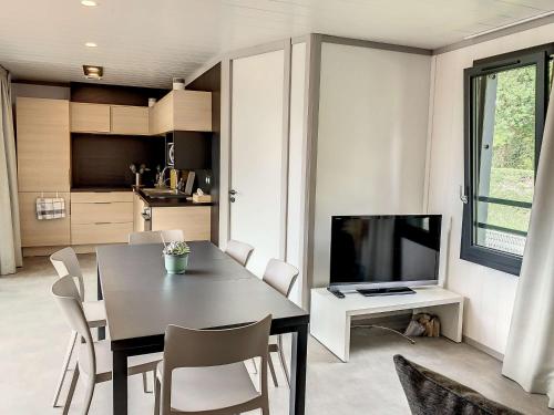 une salle à manger avec une table et une télévision dans l'établissement Chalet à Jullouville - 6 couchages, piscine chauffée, proche plage et commerces - FR-1-361-521, à Jullouville