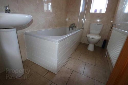 a bathroom with a tub and a toilet and a sink at Iris House in Belfast
