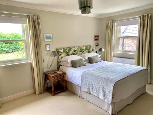 a bedroom with a large bed and two windows at Coullie Stays in Auchenblae