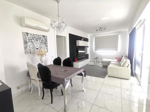 Sala de estar blanca con mesa de comedor y sillas en Happy Tucan, en Lárnaca