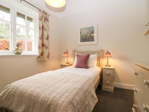 a bedroom with a white bed and two windows at West Cottage - Tarvit in Cupar