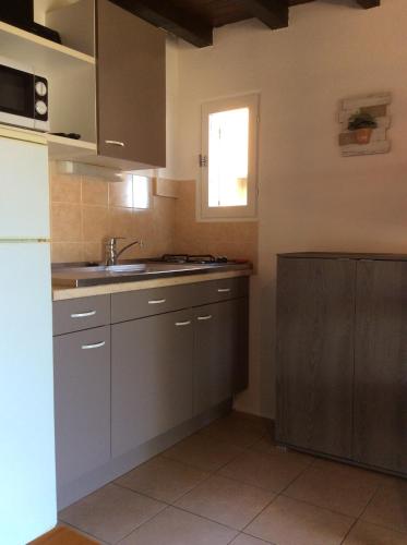 a kitchen with gray cabinets and a sink and a window at Résidence île de beauté in Propriano