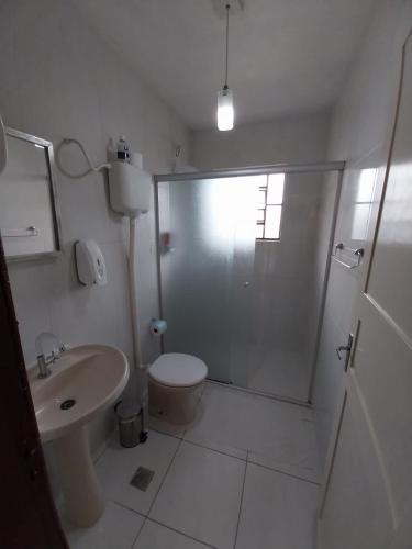 uma casa de banho com um chuveiro, um WC e um lavatório. em Apartamento no centro em Canela