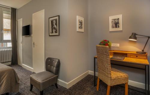 a hotel room with a desk and a chair at Le Nouvel Hôtel in Oyonnax