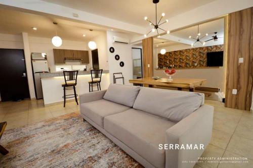 a living room with a couch and a kitchen at Departamento con amenidades in Cancún