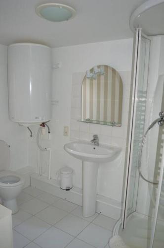 une salle de bain blanche avec un lavabo et des toilettes dans l'établissement Maison de gardien chauffée au bois avec petit déj, à Charolles