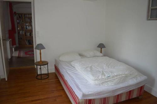 une chambre avec un lit avec des draps blancs et une lampe dans l'établissement Maison de gardien chauffée au bois avec petit déj, à Charolles