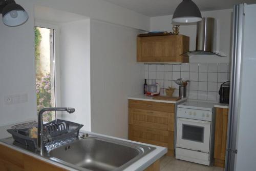 une cuisine avec un évier et une cuisinière dans l'établissement Maison de gardien chauffée au bois avec petit déj, à Charolles