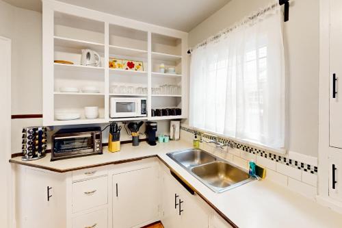 a kitchen with white cabinets and a sink and a window at Sunnyside Up in Seattle
