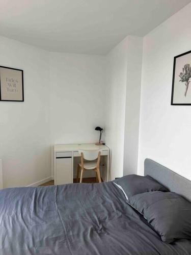 ein Schlafzimmer mit einem Bett und einem Schreibtisch mit einem Stuhl in der Unterkunft Appartement bord de Seine in Choisy-le-Roi