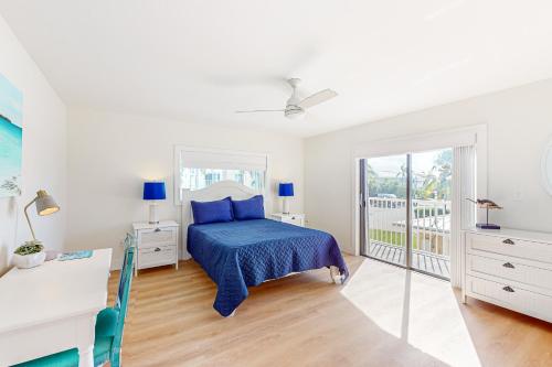 a bedroom with a blue bed and a balcony at Sea Pointe on the Canal in Key Colony Beach