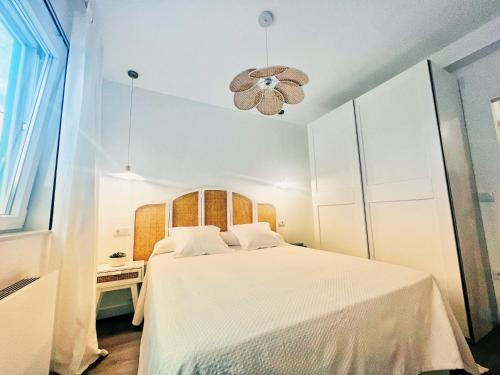 a bedroom with a white bed and a chandelier at The Cliffs - VilaTurquesa B in Viveiro