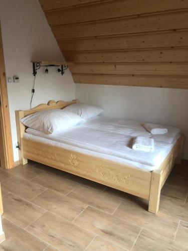 a bed in a room with a wooden ceiling at Domki nad potokiem in Białka Tatrzańska