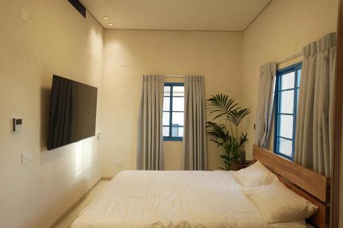 Schlafzimmer mit einem großen Bett und Fenstern in der Unterkunft MORI HOUSE in Bet Scheʼan