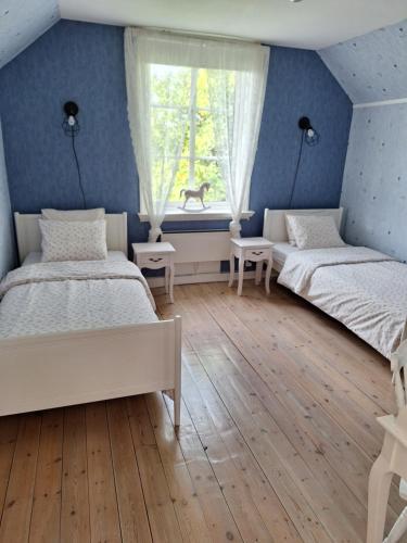 HästvedaにあるHotell Vita Hästen Hästvedaの青い壁の客室で、ベッド2台、窓が備わります。