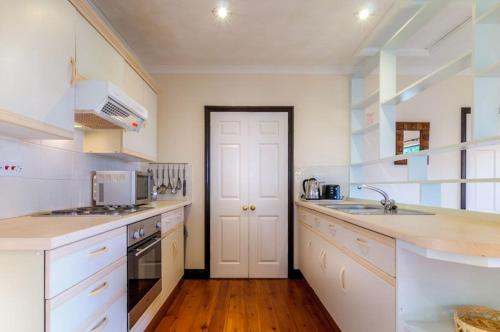 a white kitchen with a sink and a stove at Shilbury Retreat Cottage in Perranporth