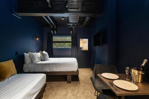a blue room with two beds and a table and a dining room at Abstract Hotel & Residences in Auckland