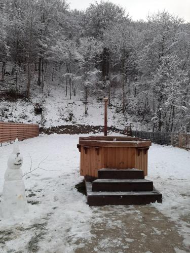 a snowman is standing next to a wooden structure at Casa Ele in Frăsinet