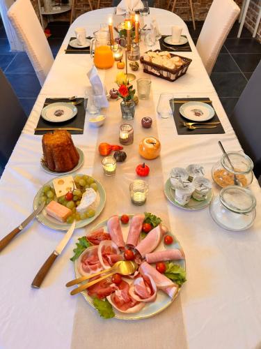 La Grange Aux Hirondelles - Chambre romantique في Woignarue: طاولة طويلة عليها أطباق من الطعام