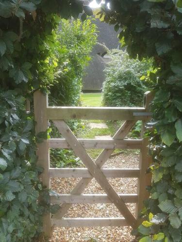 a wooden gate in the middle of a garden at Delightful 3bed thatched Cottage in Stockbridge