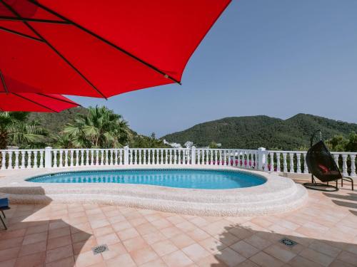 una sombrilla roja sentada junto a una piscina en Belvilla by OYO Monte Perdido, en Cala Llonga