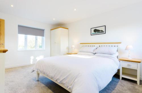 ein weißes Schlafzimmer mit einem großen Bett und einem Fenster in der Unterkunft Ivy Chimney Cottage in Porthtowan