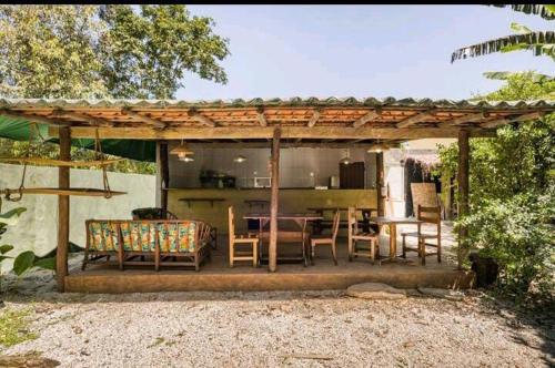 a pavilion with a table and chairs and a kitchen at Prumirim Surf Suítes in Ubatuba