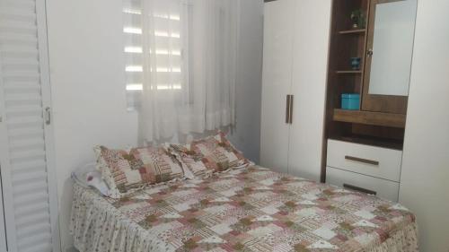 um quarto com uma cama com uma colcha e uma janela em Familia Rodrigues no Guarujá