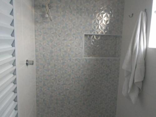y baño con ducha y pared de piedra. en Familia Rodrigues en Guarujá