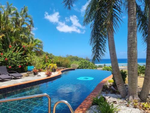 a swimming pool with palm trees and the beach at Black Rock Villas in Rarotonga