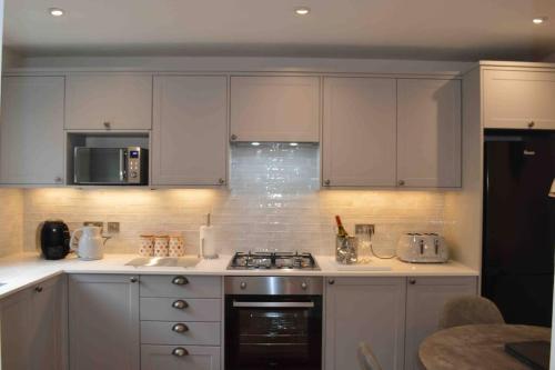uma cozinha com armários brancos e um forno com placa de fogão em Riverside House Lancaster - 2 bedroom house em Lancaster