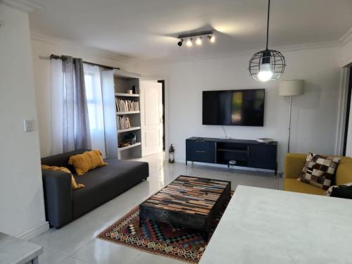 uma sala de estar com um sofá e uma televisão em G’s Self Catering Apartments na Cidade do Cabo