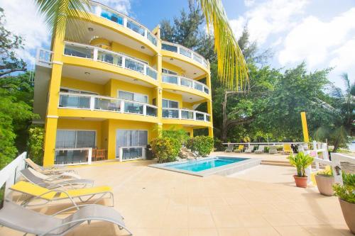ein gelbes Gebäude mit einem Pool und Stühlen in der Unterkunft Del Playa #2 Condo in West End