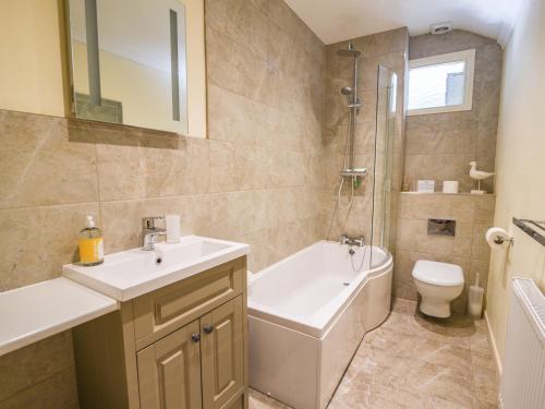 een badkamer met een wastafel, een bad en een toilet bij Nutwood in Charmouth