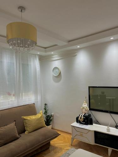 a living room with a couch and a flat screen tv at Stan na dan Mercur in Sremska Kamenica